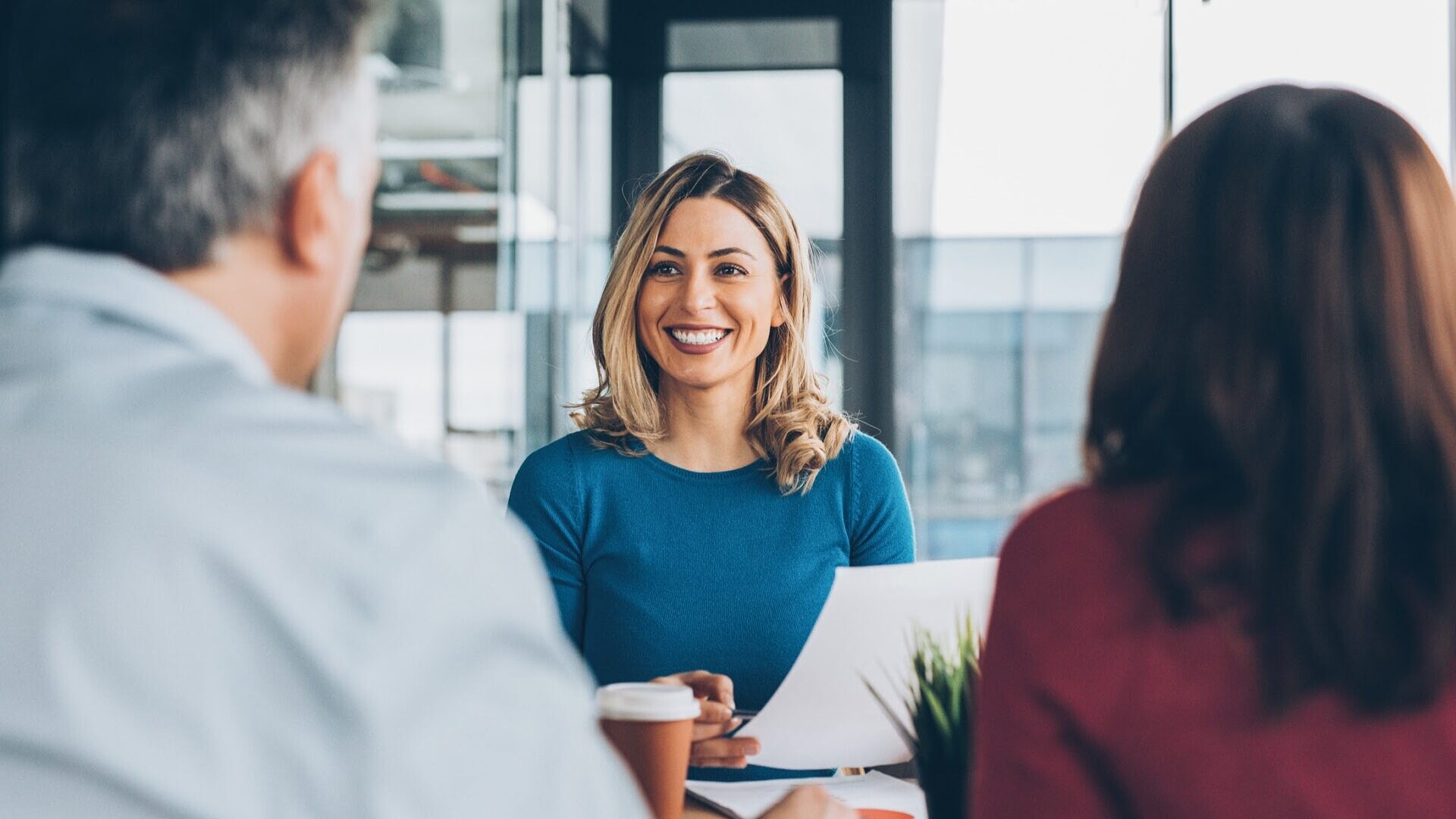 Mulher sorrindo em reunião com um casal