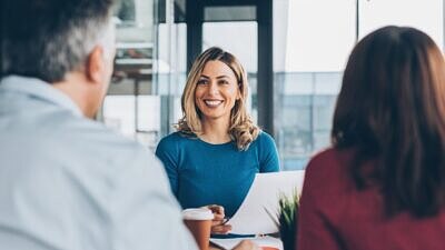 Mulher sorrindo em reunião com um casal